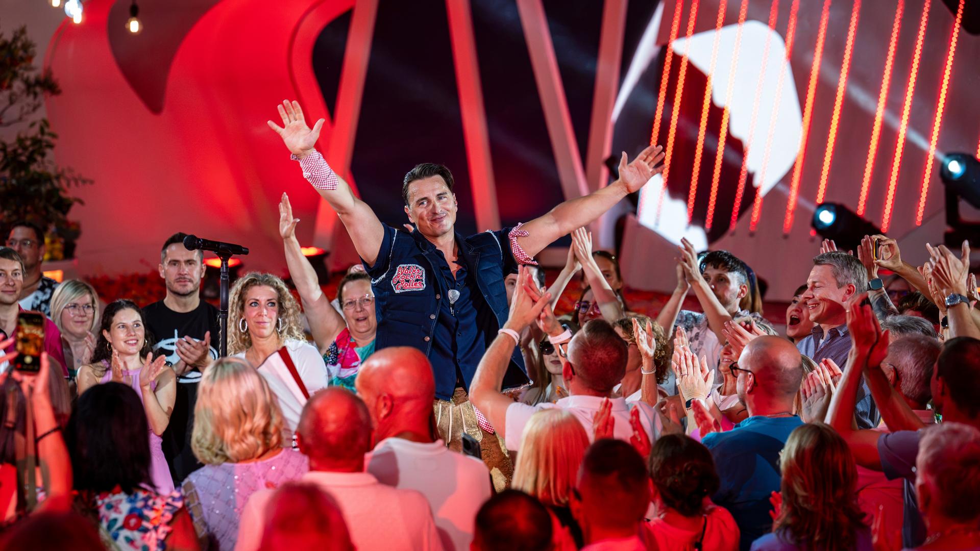 "Die Giovanni Zarrella Show - Die große Sommerparty": Andreas Gabalier steht inmitten des Publikums in der Arena des "Fernsehgartens". Beide Arme hat er nach oben gestreckt und lächelt zu den Menschen, die klatschend und feiernd zu ihm schauen.