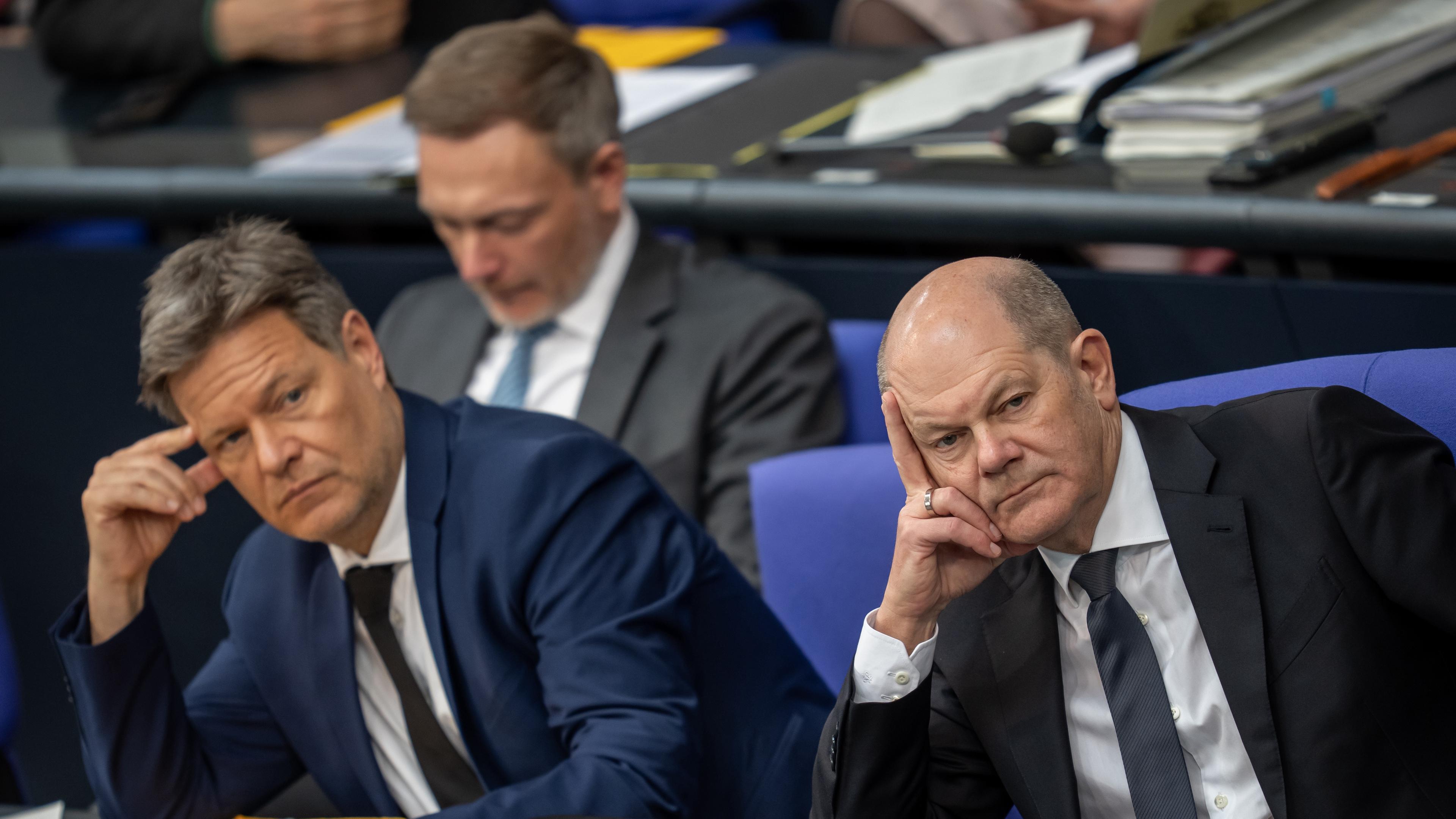Bundeskanzler Olaf Scholz (r, SPD), Robert Habeck (M, Bündnis 90/Die Grünen), Bundesminister für Wirtschaft und Klimaschutz, und Christian Lindner (FDP), Bundesminister der Finanzen, verfolgen im Bundestag die Aussprache