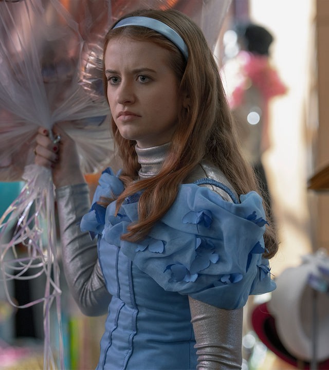 "Extraordinary - Habenichtse": Jen (Máiréad Tyers) steht grimmig blickend in einem Geschäft. In ihrer Hand hält sie ein Strauß Helium-Luftballons.