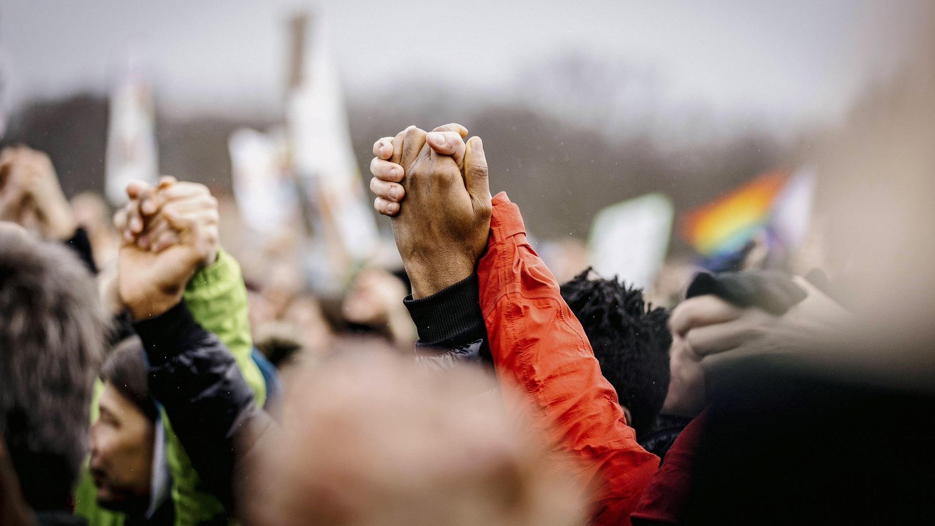 Nahaufnahme von einer Menschenmenge, mit hochgereckten Händen, die sich halten