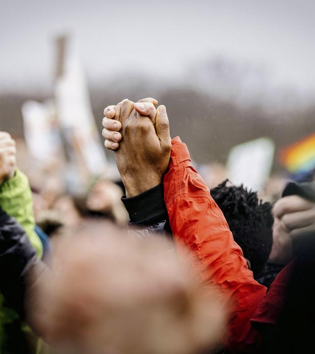 Nahaufnahme von einer Menschenmenge, mit hochgereckten Händen, die sich halten