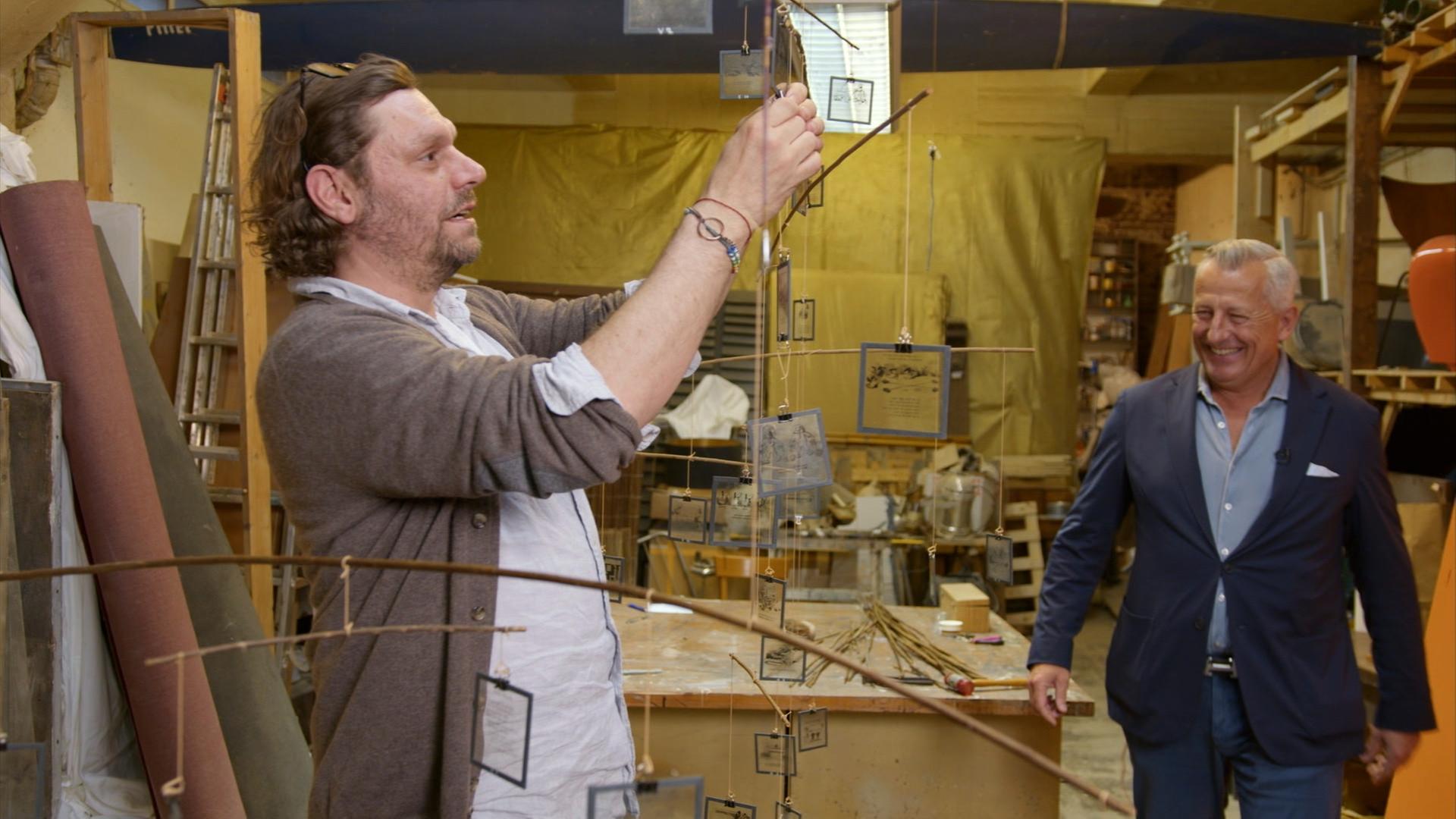 Händler Markus Wildhagen in einer Werkstatt, wo ein Kollege von ihm an einem Mobile bastelt