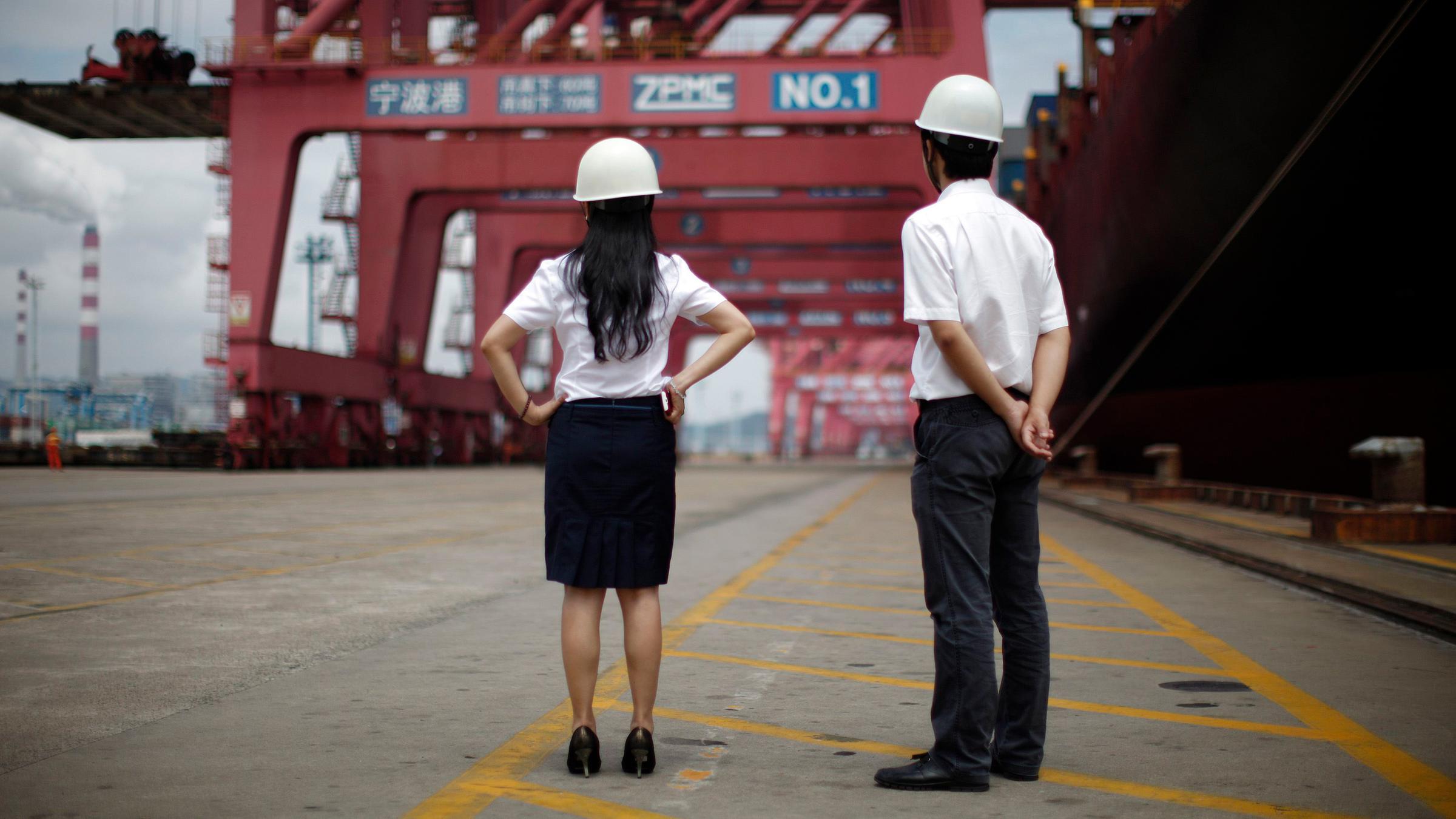 Mitarbeiter stehen vor einem Containerschiff im Hafen von Ningbo