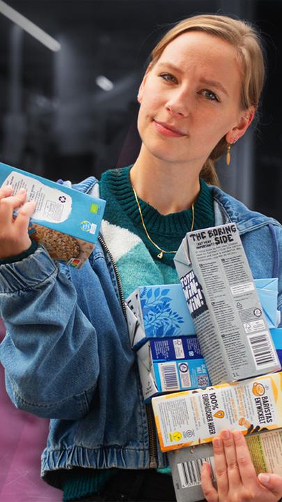 Sabrina Zimmermann hält verschiedene Verpackungen von Haferdrink in der Hand