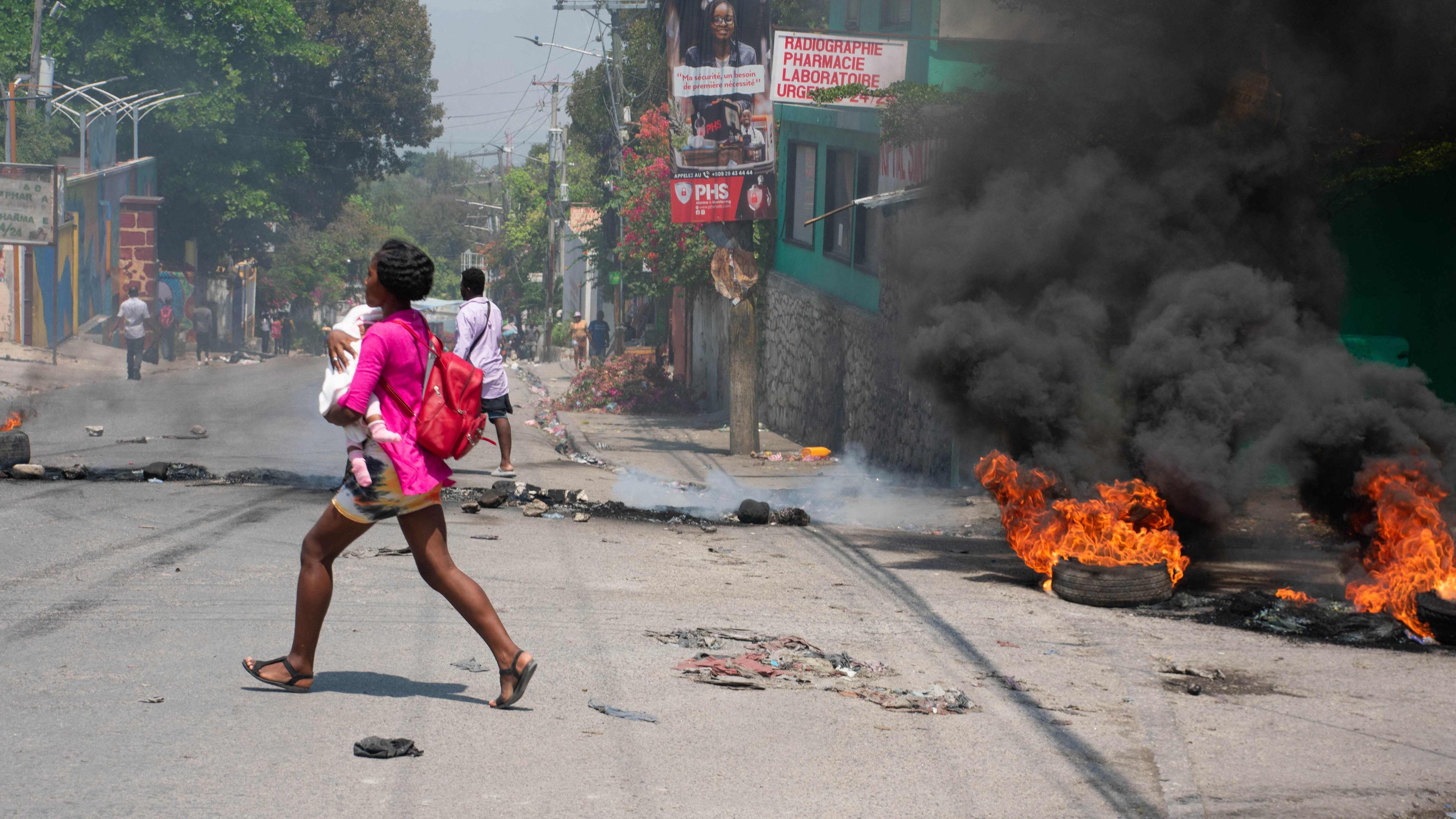 Eine Frau rennt mit einem Kind auf dem Arm, nachdem in Port-au-Prince Schüsse gefallen sind.