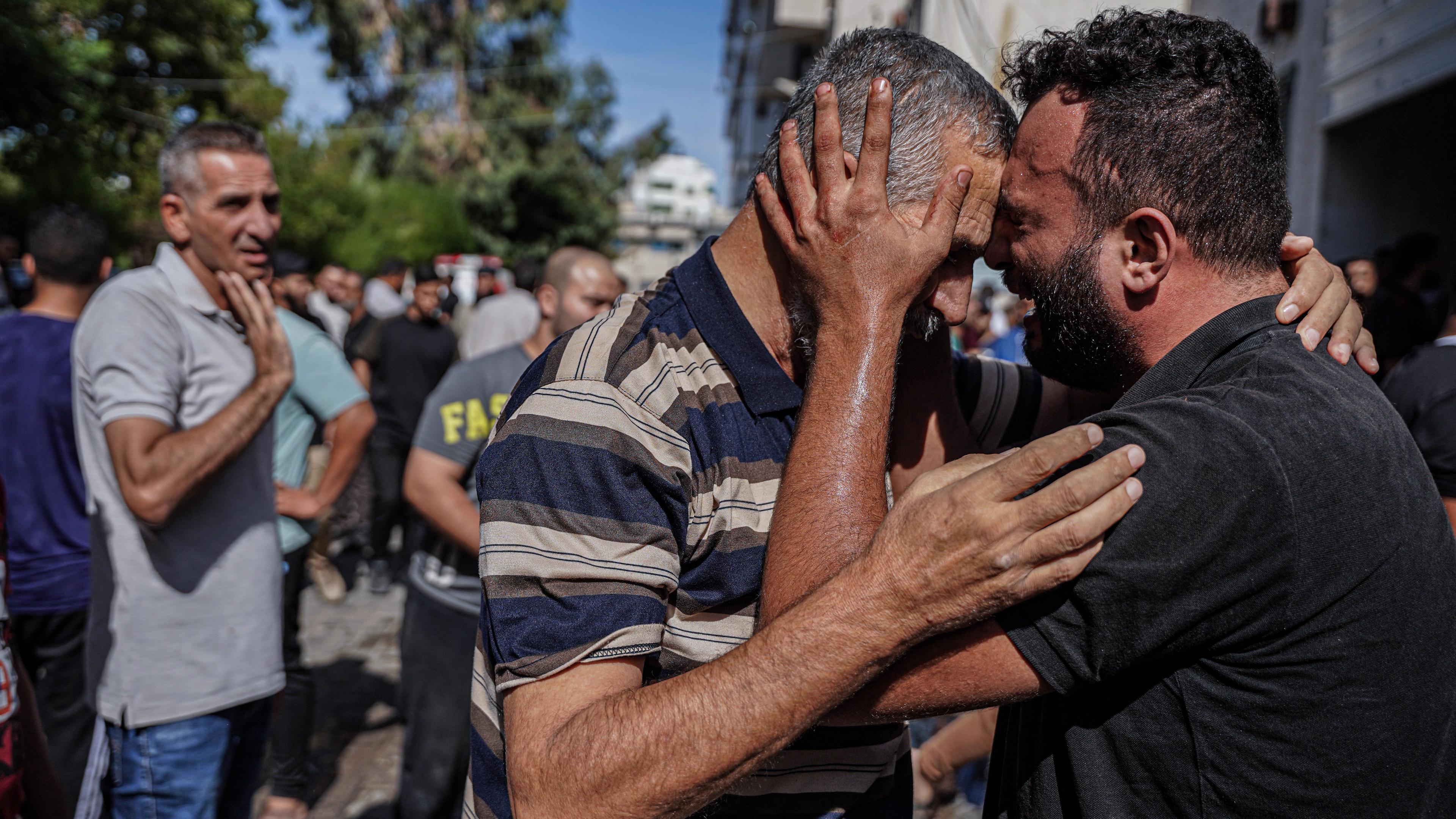 07.10.2023, Palästinensische Gebiete, Gaza: Ein Mann umarmt einen Familienangehörigen im palästinensischen Gebiet und weint.