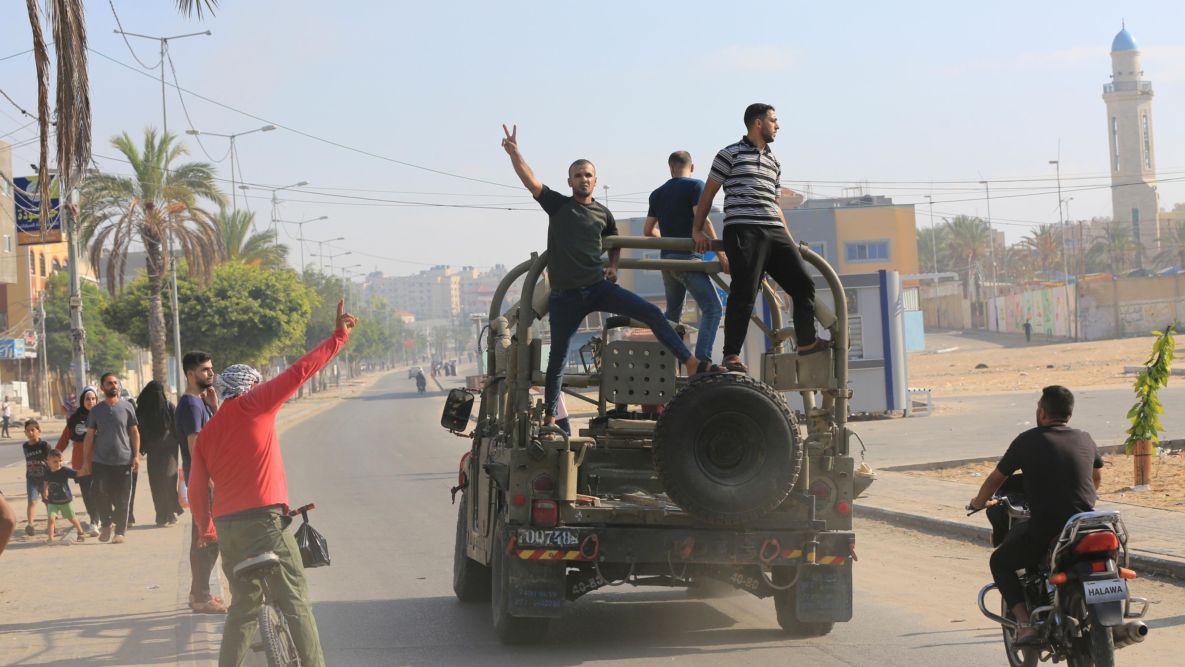 Palästinensische Gebiete, Gaza-Stadt: Palästinenser fahren auf einem israelischen Militärfahrzeug, das von einem von Hamas-Kämpfern überrannten Armeestützpunkt in der Nähe der Grenze zum Gazastreifen mitgenommen wurde.