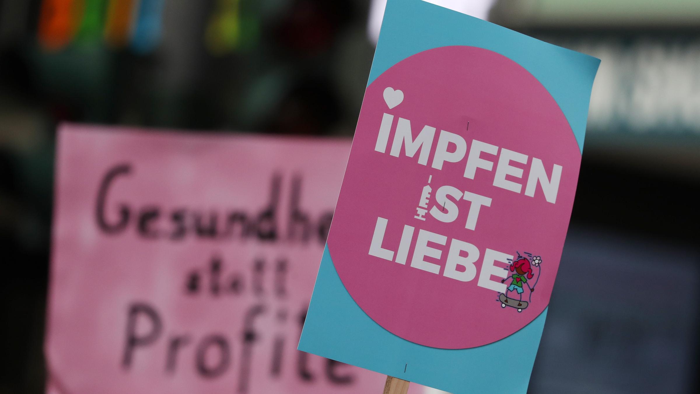 Plakate bei Demonstrationen mit den Aufschriften "Impfen ist Liebe" und "Gesundheit statt Profite". Deutschland, Hamburg. 