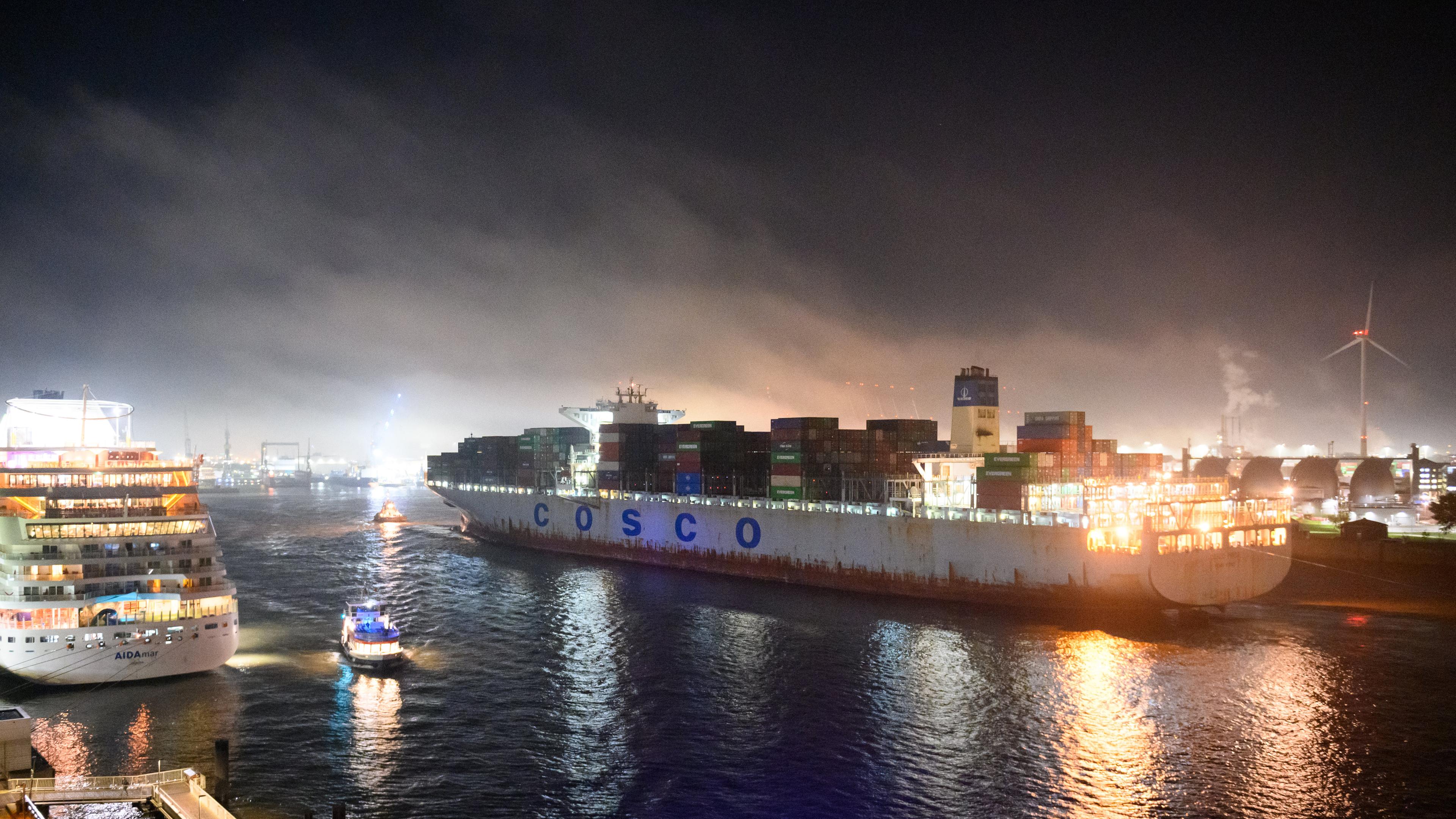Der Hamburger Hafen bei Nacht. Ein Schiff mit dem Aufdruck "Cosco" läuft in den Hafen ein.