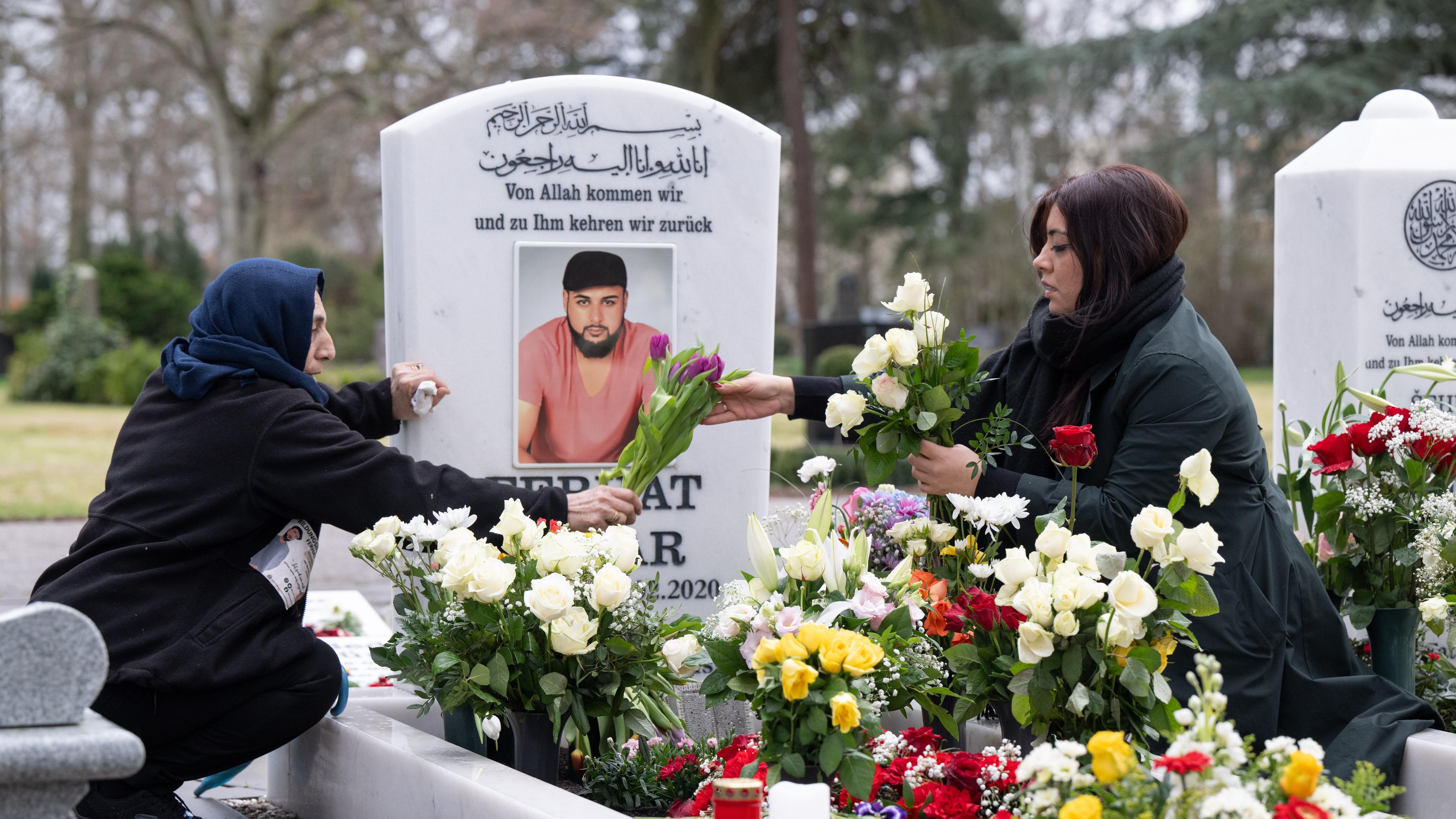  Zwei Frauen schmücken das Grab von Ferhat Unvar auf dem muslimischen Gräberfeld auf dem Hauptfriedhof in Hanau mit Blumen