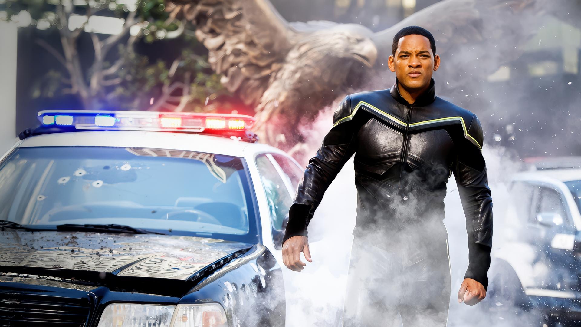 "Hancock": Hancock (Will Smith) steht in einem schwarzen Superhelden-Anzug neben einem Polizeiauto. Er blickt skeptisch nach vorn. Im Hintergrund ist ein großer Greifvogel zu sehen.