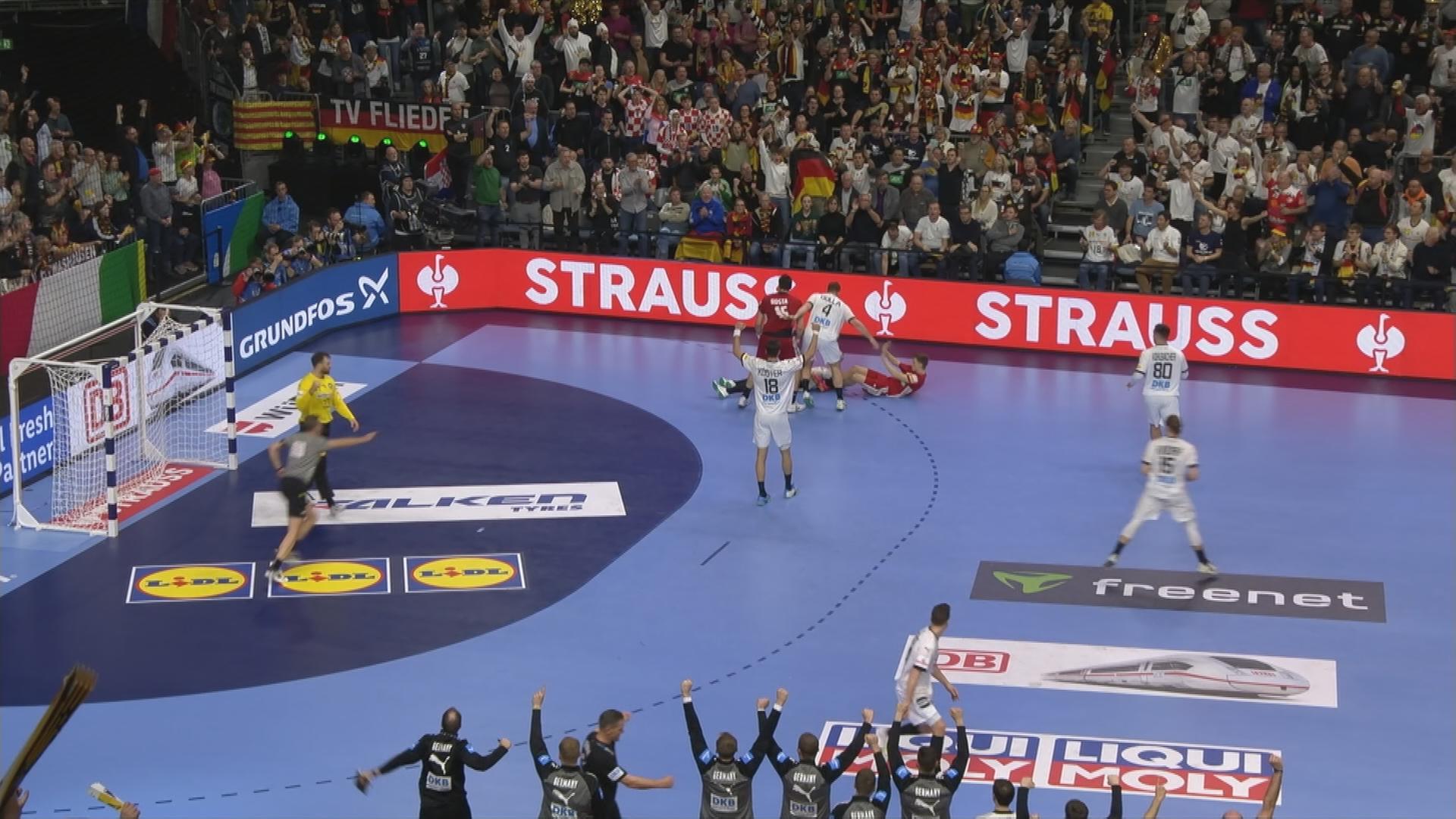 Auf dem Bild ist das deutsche Handballteam auf dem Spielfeld zu sehen.