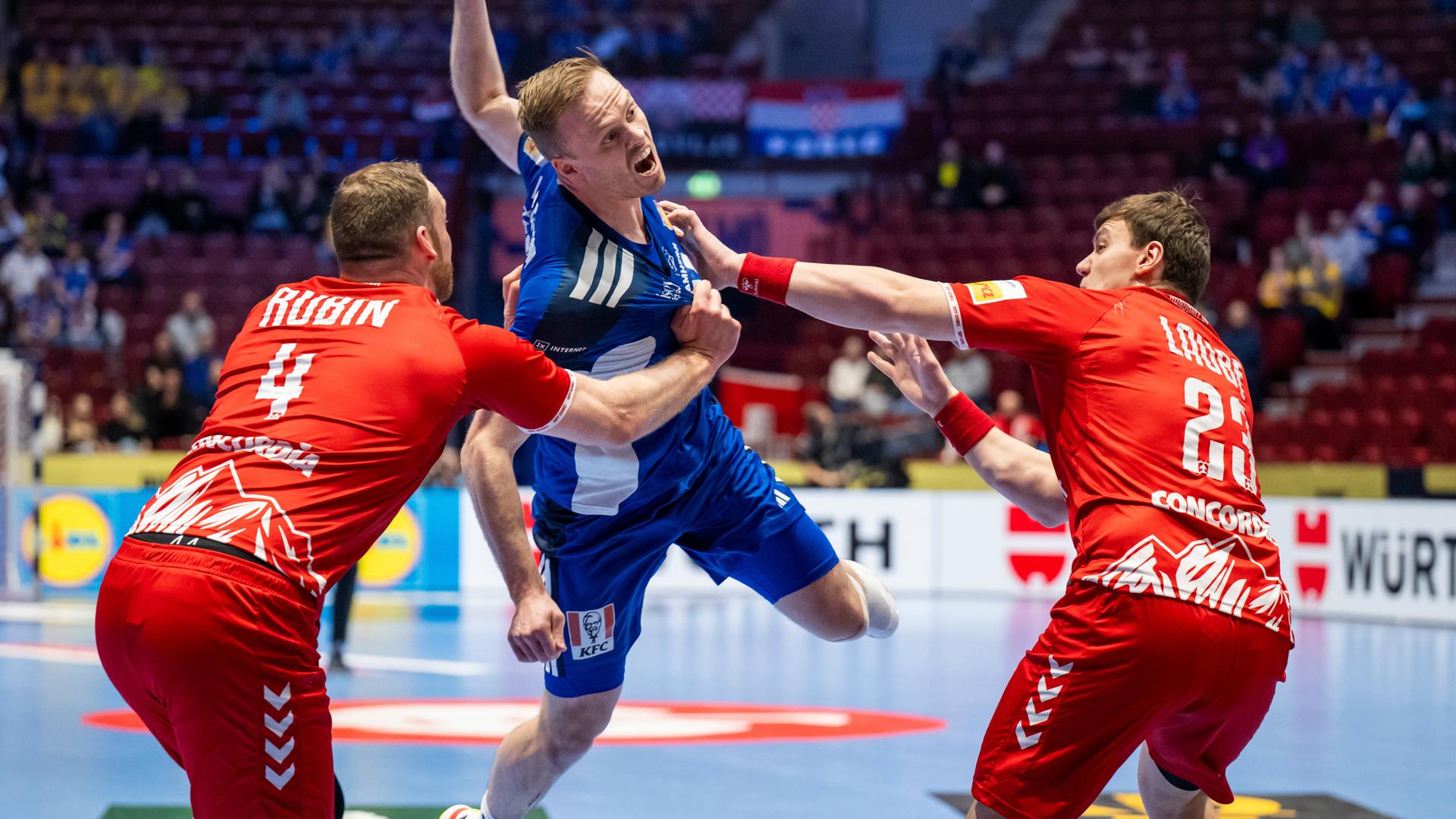 Islands Ómar Ingi Magnússon im Zweikampf mit den Schweizern Lenny Rubin (links) und Lukas Laube während des Handballspiels der Männer zwischen der Schweiz und Island in Malmö, Schweden.