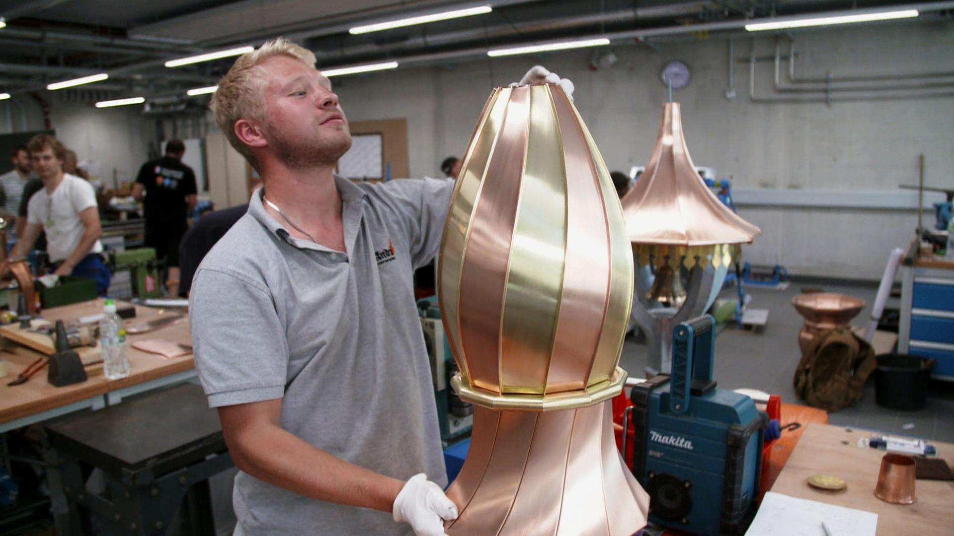 "Handwerker gesucht - Ein Berufsstand in der Krise": Ein junger Mann bearbeitet ein hohes, ovalförmiges Metallstück.