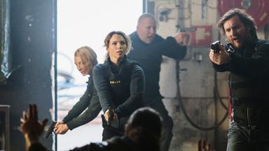 "Hanna Svensson - Blutsbande": Tina (Sofia Ledarp) und Björn (Magnus Krepper) stehen mit vorgehaltenen Waffen in einem heruntergekommenen Schuppen und halten mehrere Rocker in Schach.