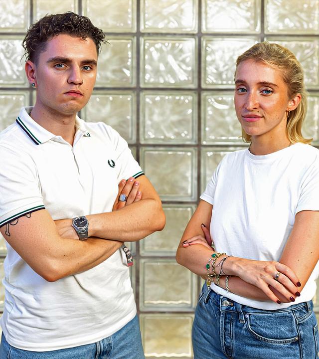 Jurastudent Hannes Kreschel und Podcasterin Pauline von Pezold stehen mit verschränkten Armen nebeneinander und schauen in die Kamera.