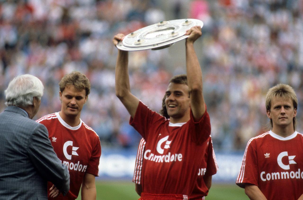 Hans Dieter Flick (Mitte) präsentiert im Fußballstadion die Meisterschale - der FC Bayern ist deutscher Meister der Saison 1988/1989. Hinten links ist Roland Wohlfarth hinten rechts und Hans Dorfner zu sehen.