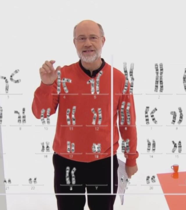 Harald Lesch hinter einer Tafel mit Abbildung von Genen