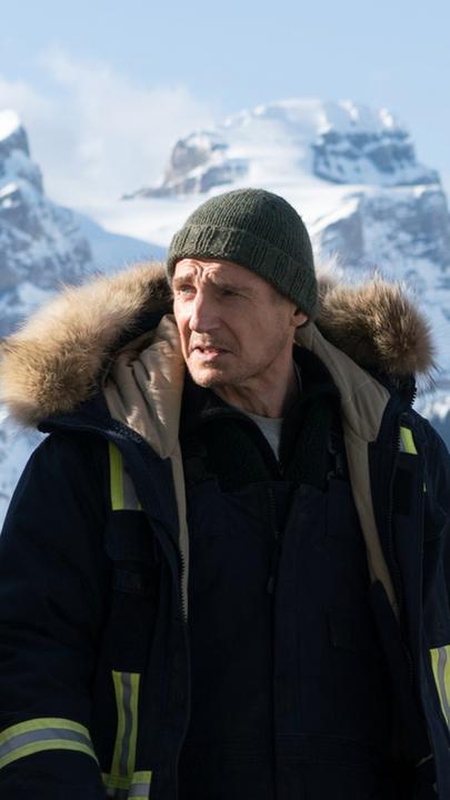 Nels Coxman (Liam Neeson) in Großaufnahme vor einem Bergpanorama.