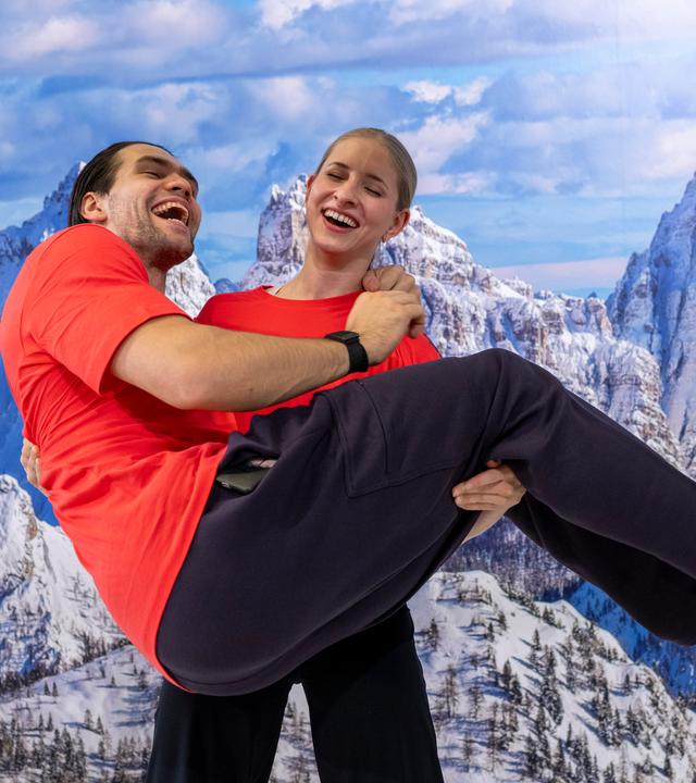 Die Eiskunstläufer Minerva Fabienne Hase und Nikita Volodin stehen während der Einkleidung für die Winterspiele in Mailand vor einer Fototapete zusammen.
