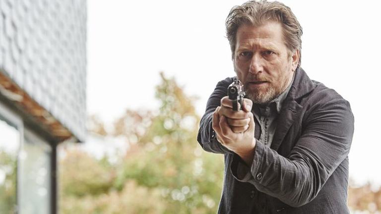 "Hattinger und der Nebel": Alfons Hattinger (Michael Fitz) in Großaufnahme mit gezogener Waffe.