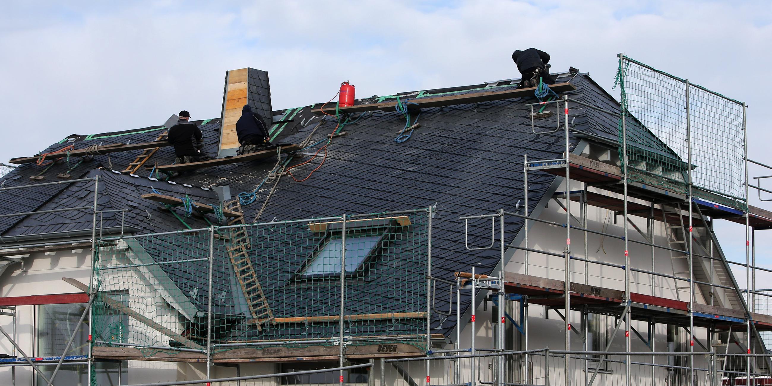 Rheinland-Pfalz, Nieder-Olm: Dachdecker arbeiten in einem Neubaugebiet am Dach eines Hauses. Archivbild