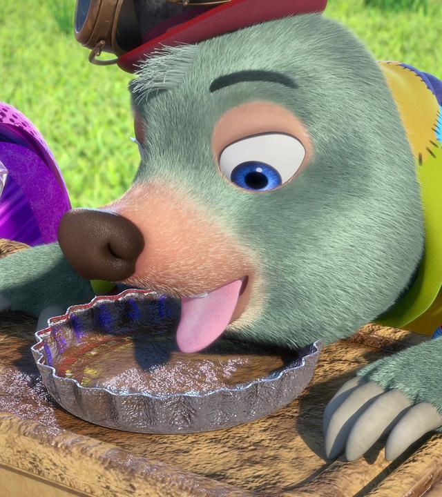 Moley sitzt an einem Tisch mit weiteren Maulwürfen. Vor ihm steht ein fast leerer Teller, über den er sich mit ausgestreckter Zunge beugt.