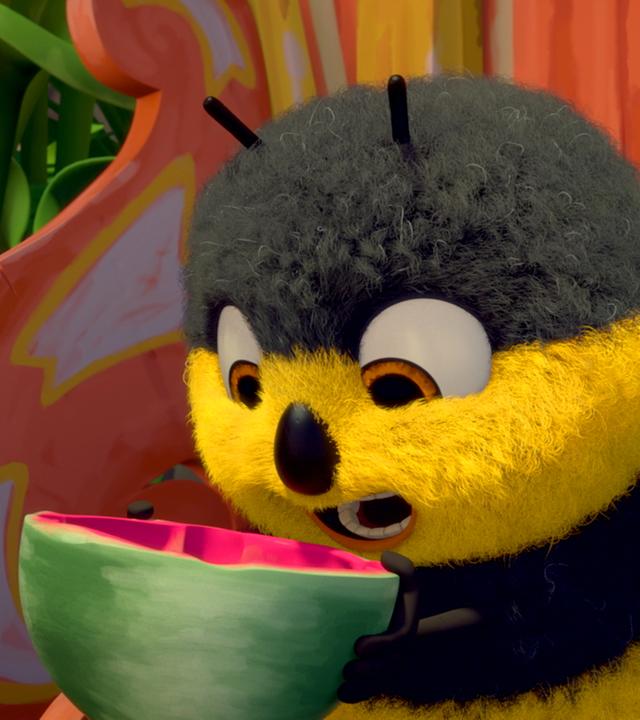 Hummel Heini beißt gierig in eine halbe Wassermelone hinein.
