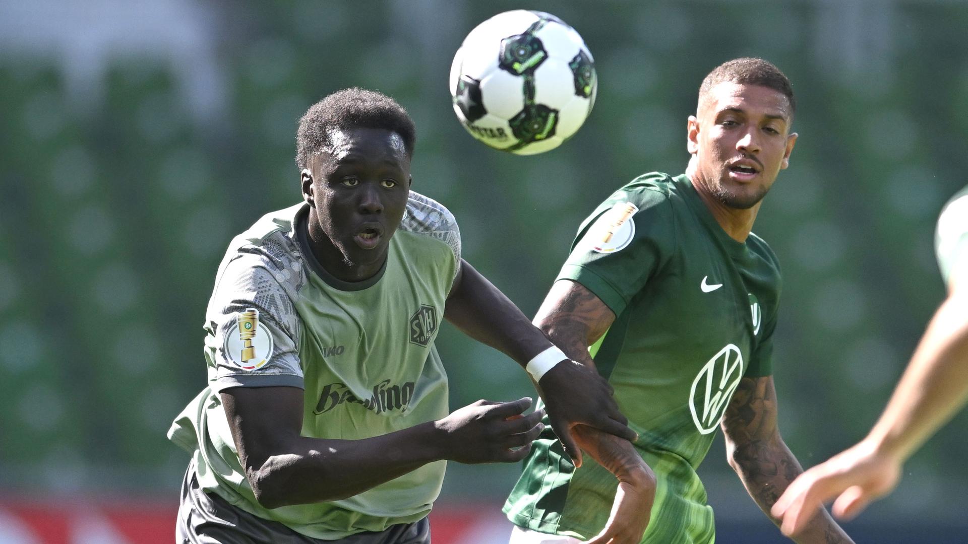 Konstantinos Koulierakis (rechts, VfL Wolfsburg) und Radin Amadou vom SV Hemelingen rennen dem Ball hinterher.