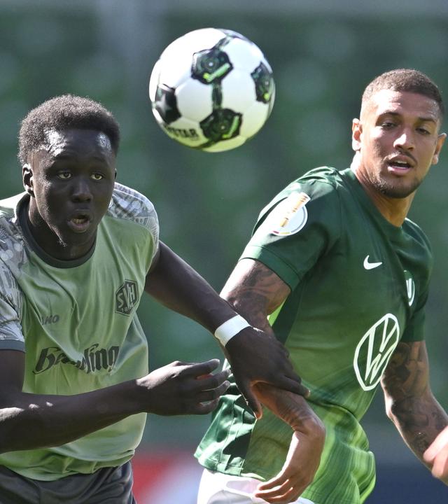Konstantinos Koulierakis (rechts, VfL Wolfsburg) und Radin Amadou vom SV Hemelingen rennen dem Ball hinterher.