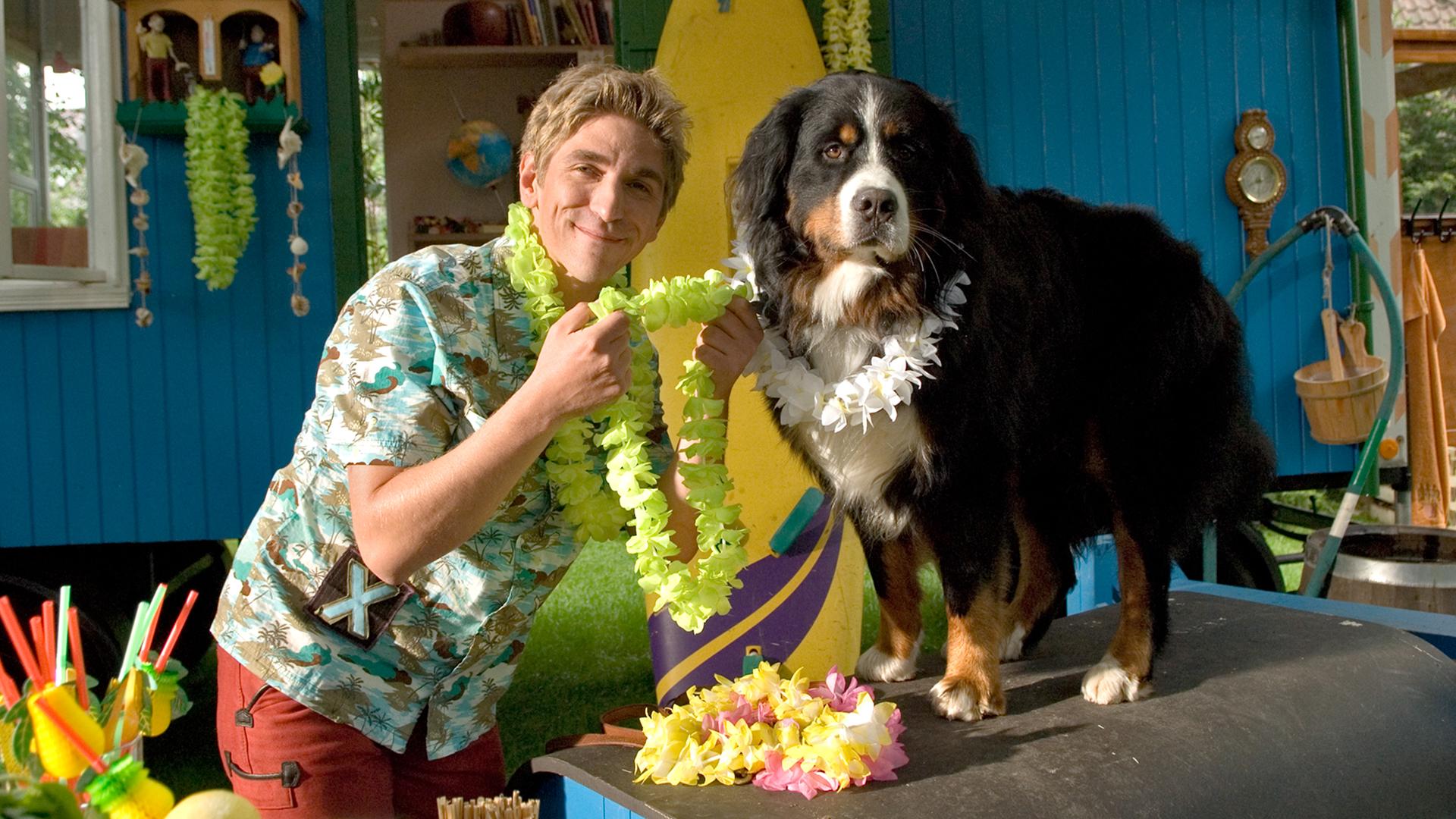 Fritz trägt eine Hawaii-Blumenkette und ist dabei Keks auch eine Kette umzulegen.