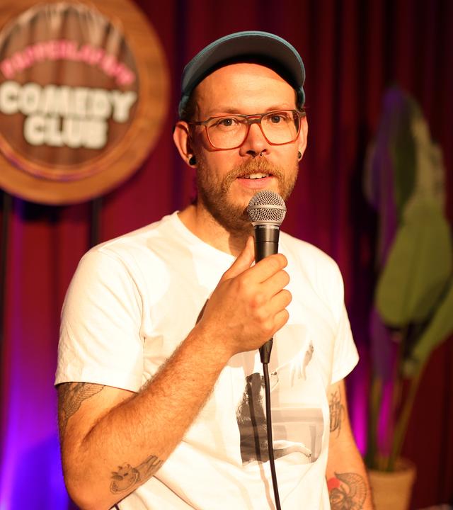 Toby Käp steht mit einem Mikrofon  auf einer Bühne