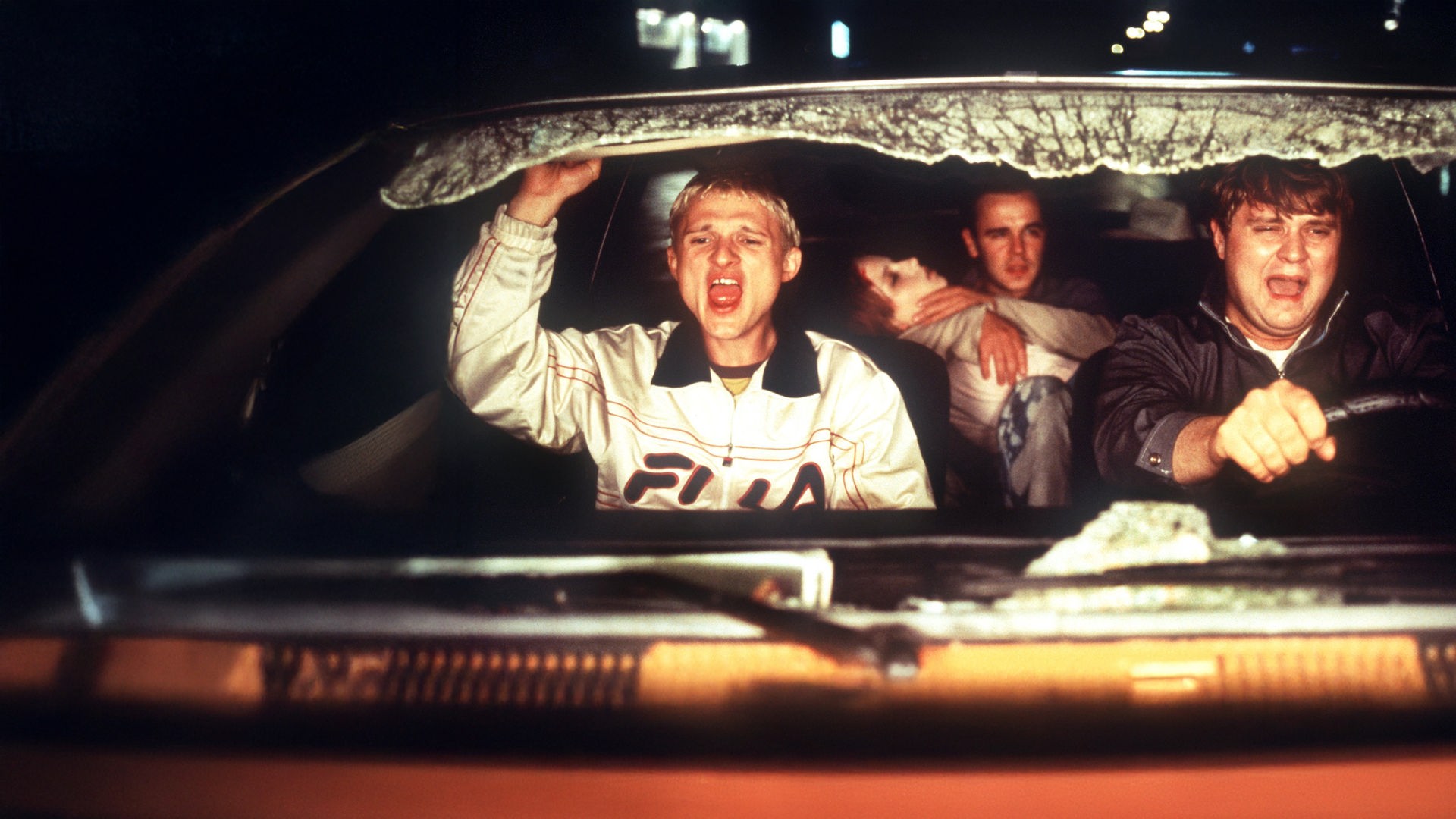 "Absolute Giganten": Ricco (Florian Lukas) und Walter (Antoine Monot) sitzen schreiend auf den Vordersitzen, während Walter das Auto steuert. Auf der Rückbank hält Floyd (Frank Giering) Telsa (Julia Hummer) im Arm, deren Augen geschlossen sind. Das Frontfenster ist zersplittert.