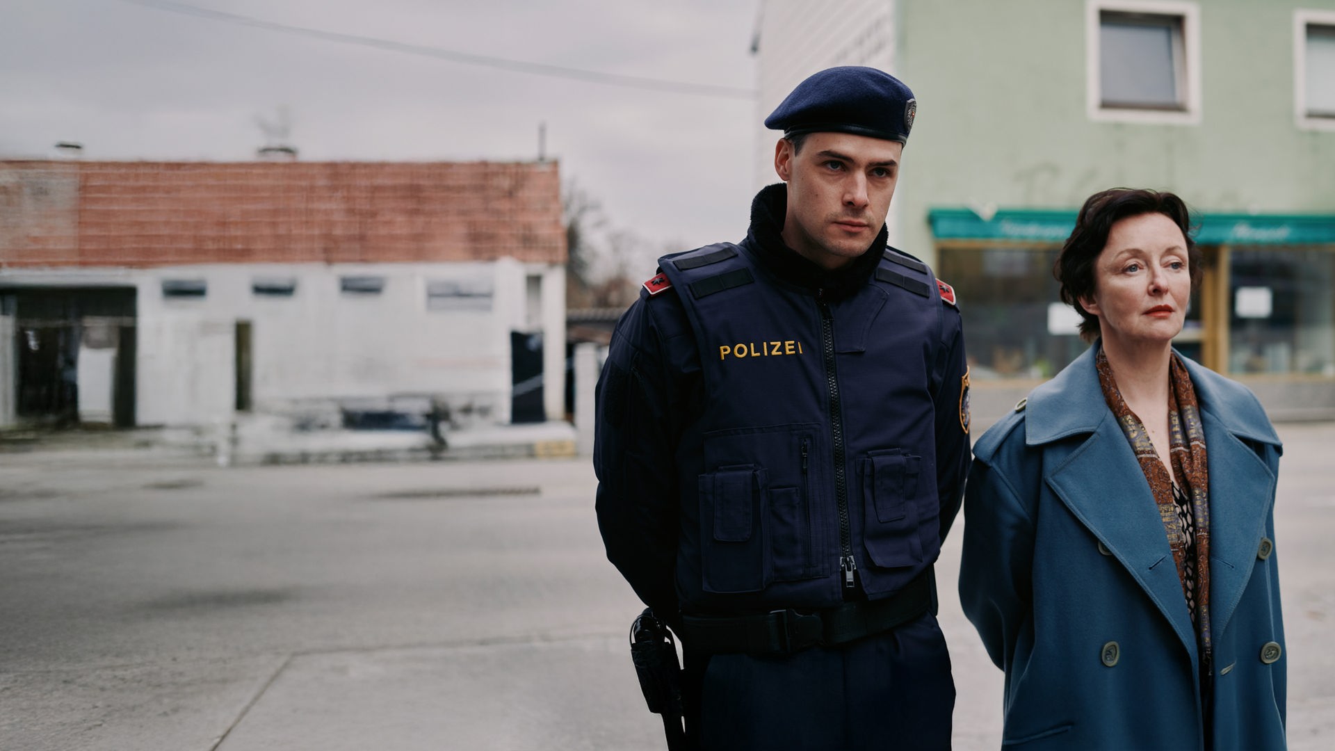 Patrick Brandl (Thomas Prenn, l.) und Marion Geyer (Regina Fritsch, r.) ermitteln in einem Mordfall. Patrick Brandl (Thomas Prenn) und Marion Geyer (Regina Fritsch) gehen zusammen die Straße entlang.