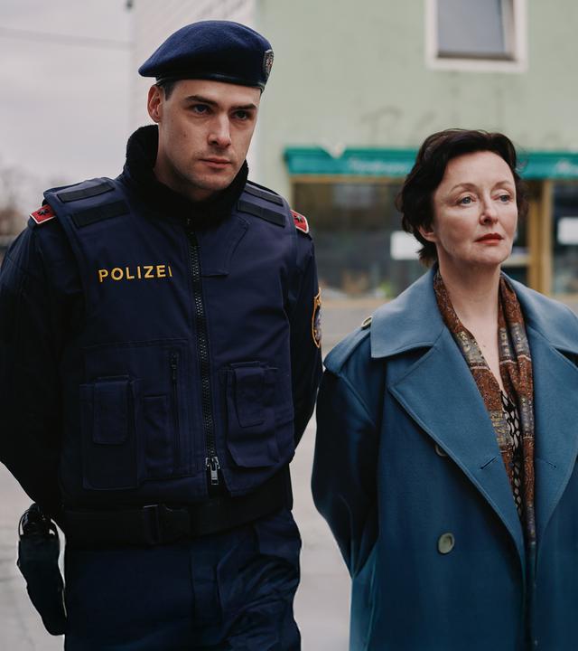 Patrick Brandl (Thomas Prenn, l.) und Marion Geyer (Regina Fritsch, r.) ermitteln in einem Mordfall. "ACHT - Ein Landkrimi": Patrick Brandl (Thomas Prenn) und Marion Geyer (Regina Fritsch) gehen zusammen die Straße entlang.