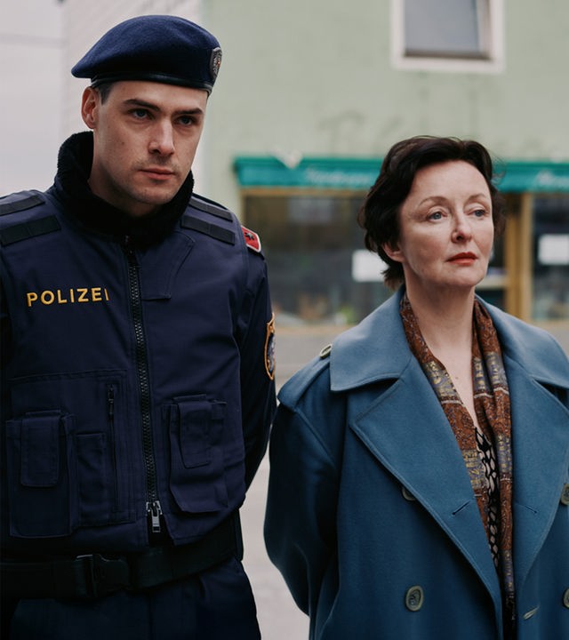 Patrick Brandl (Thomas Prenn, l.) und Marion Geyer (Regina Fritsch, r.) ermitteln in einem Mordfall. Patrick Brandl (Thomas Prenn) und Marion Geyer (Regina Fritsch) gehen zusammen die Straße entlang.