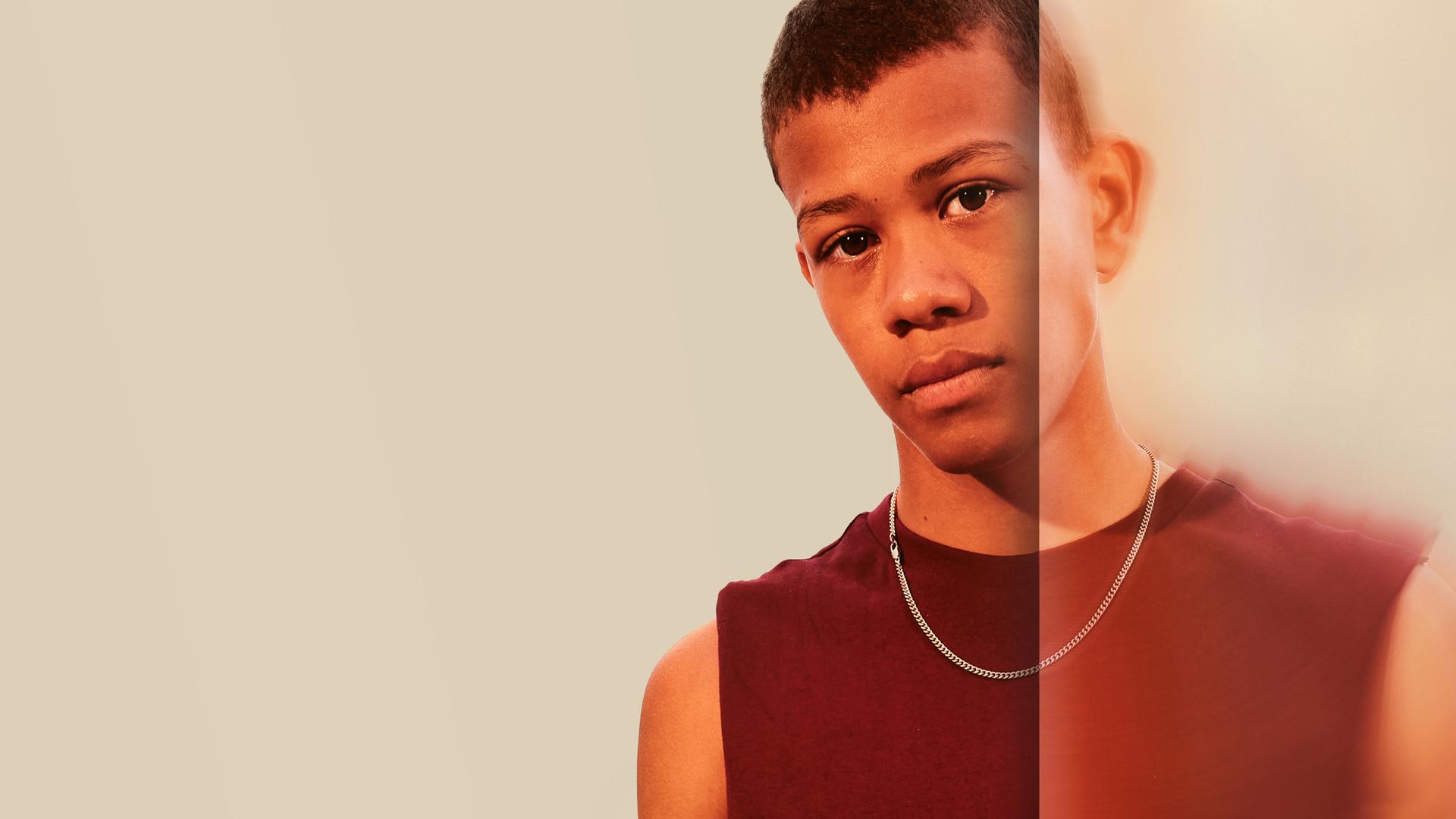 Benjamin, ein farbiger Teenager, schaut nachdenklich den Zuschauer an.