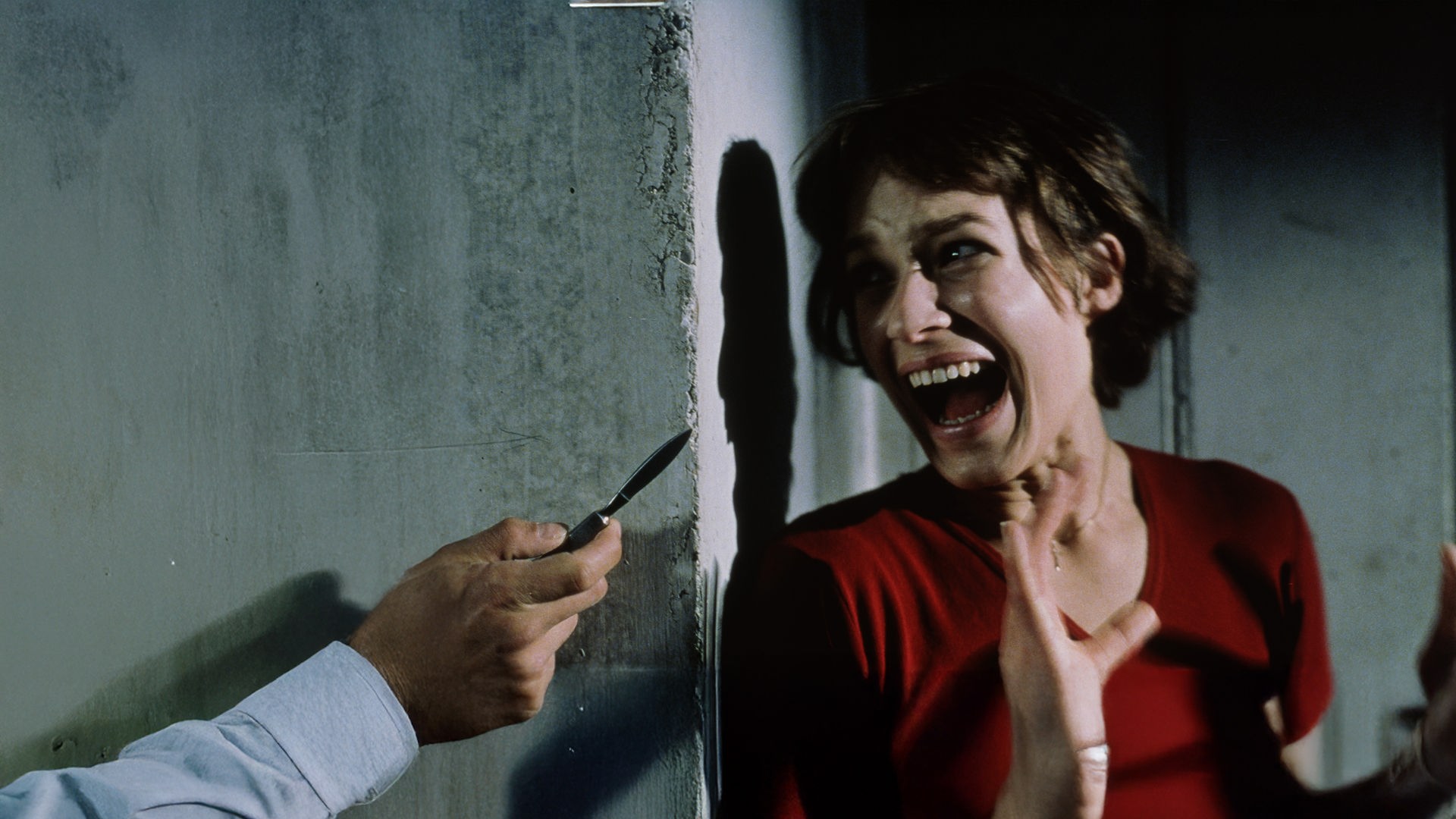 "Anatomie": Paula (Franka Potente) lehnt mit dem Rücken an der Wand und schreit angsterfüllt, während ihr Blick auf die Klinge eines Klappmessers gerichtet ist.