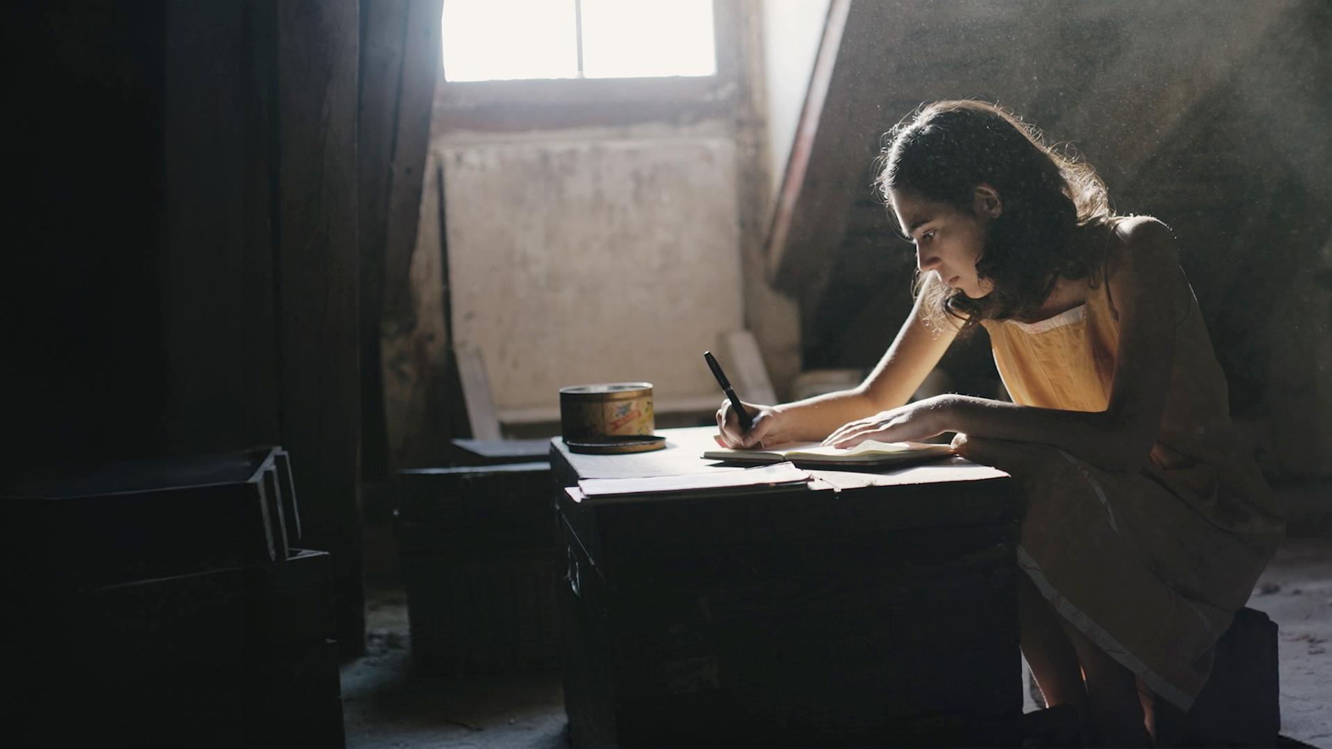 Anne Frank schreibt auf dem Dachboden in ihr Tagebuch