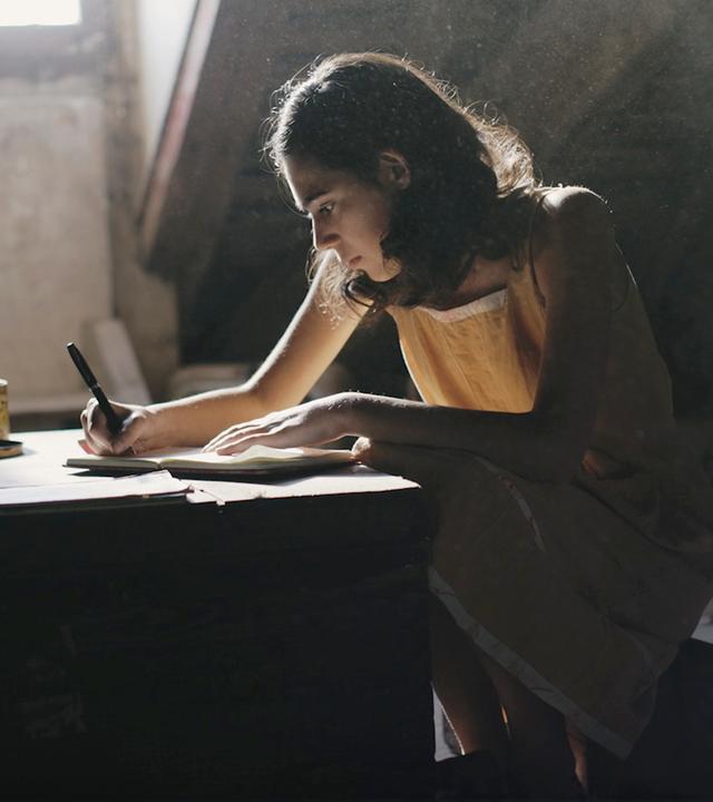 Anne Frank schreibt auf dem Dachboden in ihr Tagebuch