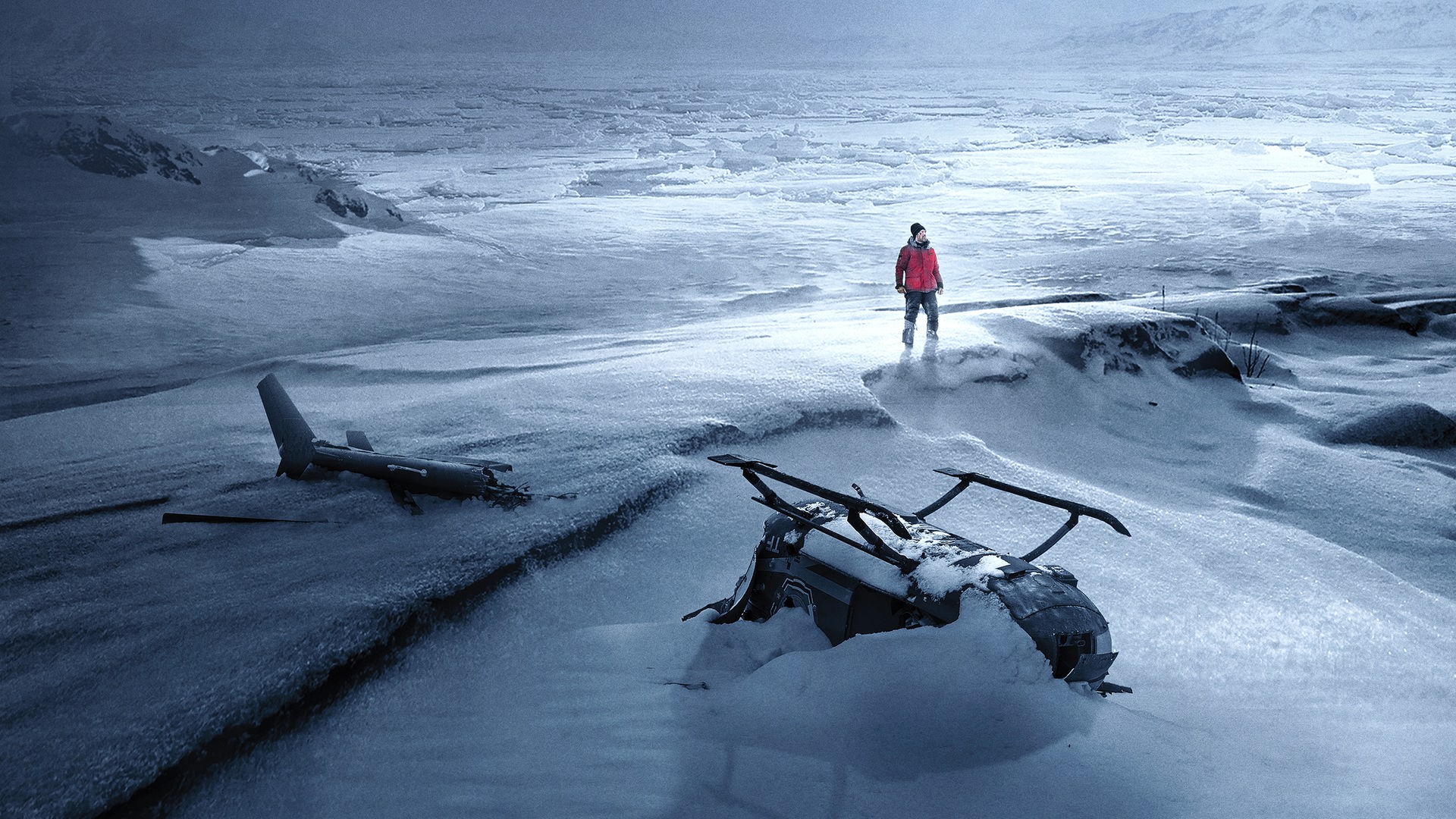 Arctic: In einer weiten, verschneiten Eislandschaft steht eine einzelne Person in roter Jacke zwischen den Wrackteilen eines Flugzeugs und eines Hubschraubers.