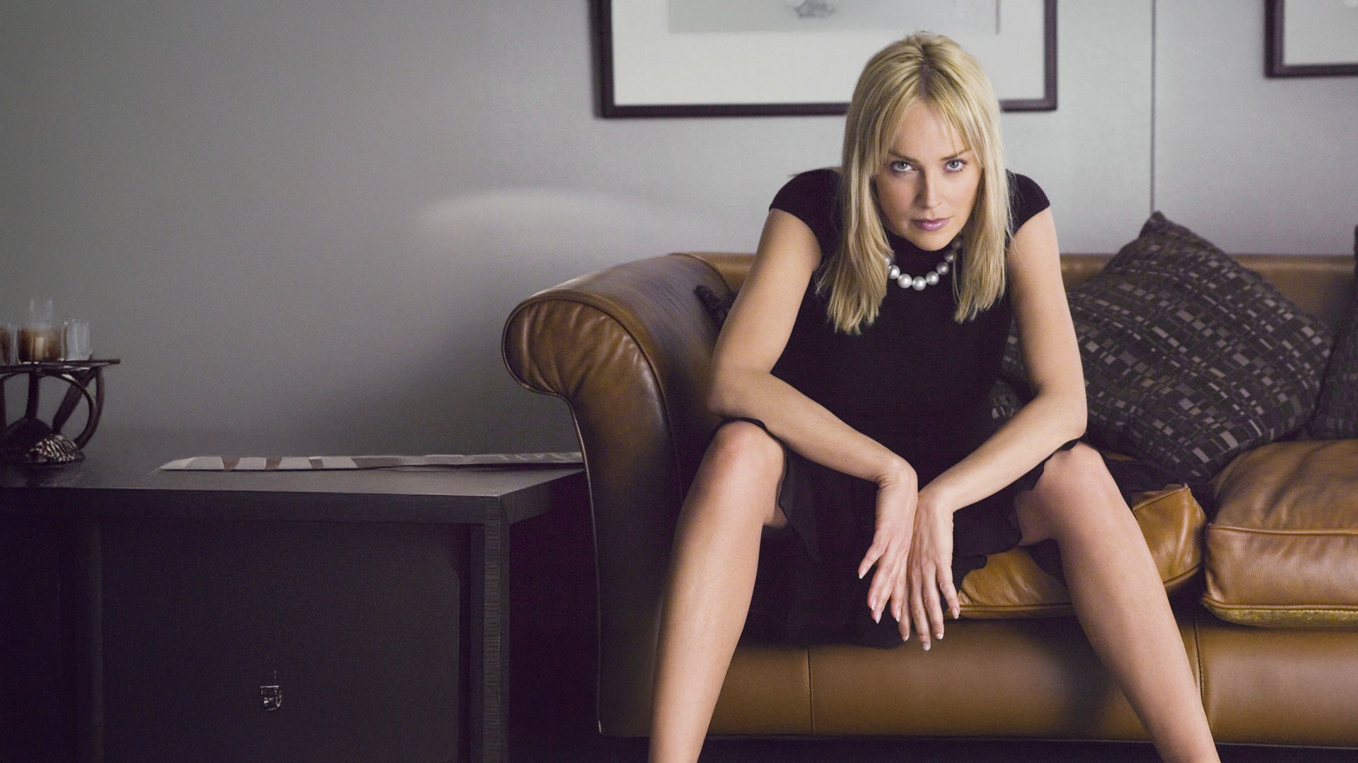 "Basic Instinct 2": Catherine Tramell (Sharon Stone) sitzt lasziv auf einem Sofa und blickt direkt in die Kamera.
