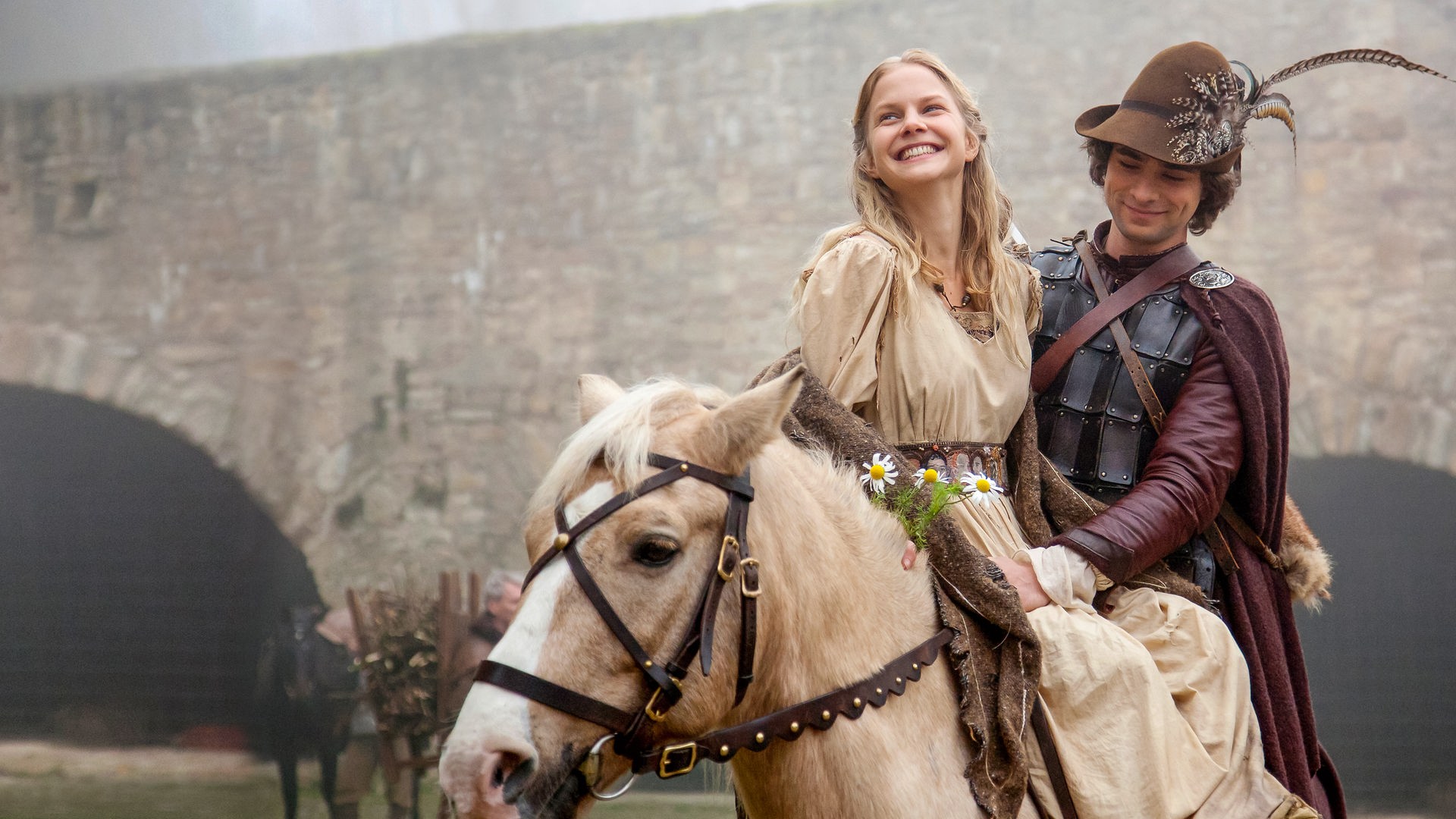 Vor dem Hintergrund der königlichen Burg sitzt Prinz Markus (André Kaczmarczyk), gekleidet wie ein Jäger, auf seinem weißen Pferd. Vor ihm, im Damensitz, Constanze (Sinja Dieks), die über das ganze Gesicht strahlt.