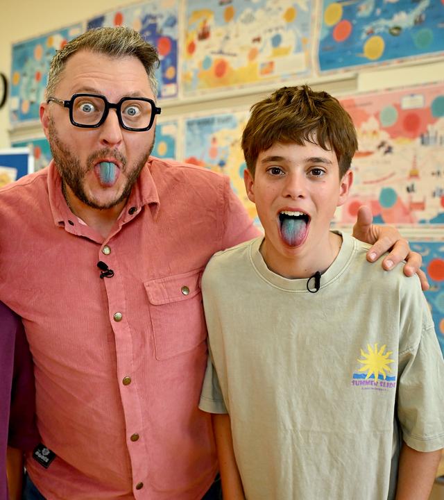 "besseresser Kids": Rejan, Sebastian Lege und Bruno (v. l. n. r.) stehen eng beieinander und strecken der Kamera ihre blau gefärbten Zungen entgegen. Im Hintergrund hängen bunte Poster. 