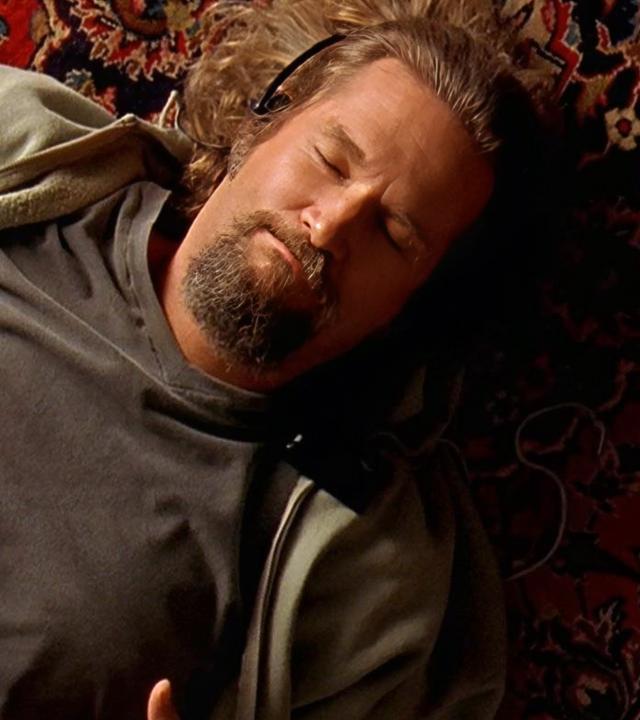 Jeff Bridges liegt auf einem Teppich und raucht