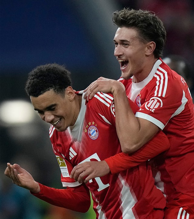 Jamal Musiala vom FC Bayern (links) feiert mit seinem Teamkollegen Tom Bischof, nachdem er im Bundesligaspiel zwischen dem FC Bayern München und Borussia Mönchengladbach in München vom Elfmeterpunkt aus das dritte Tor seiner Mannschaft erzielt hat.