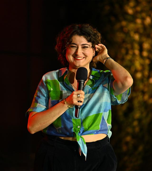 "ZDF Comedy Sommer mit Till Reiners": Matilde Keizer steht mit einem Mikrofon in der Hand auf der Bühne und spricht zum Publikum. 