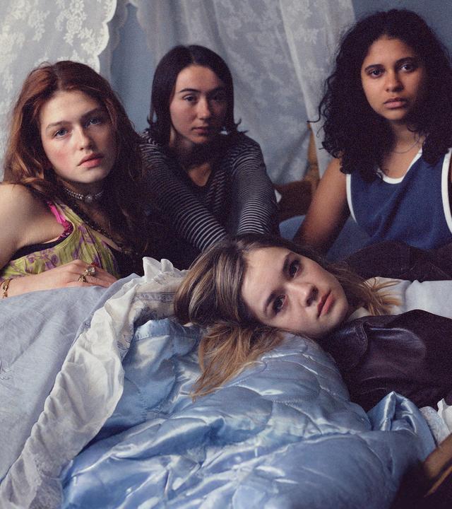 Victoria (Sonja Weißer), Malou (Zoe Stein), Katharina (Lea Drinda) sitzen auf einem mit Spitze dekorierten Bett, während Ricky (Safinaz Sattar) liegt.