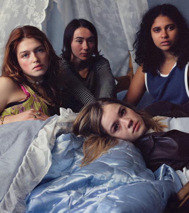 Victoria (Sonja Weißer), Malou (Zoe Stein), Katharina (Lea Drinda) sitzen auf einem mit Spitze dekorierten Bett, während Ricky (Safinaz Sattar) liegt.