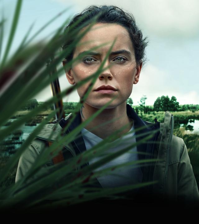 Plakatmotiv: Helena (Daisy Ridley) steht teilweise von Schilf verdeckt vor einem Sumpfgebiet und blauem Himmel mit Wolken. Sie trägt ein Gewehr über ihrer Schulter.